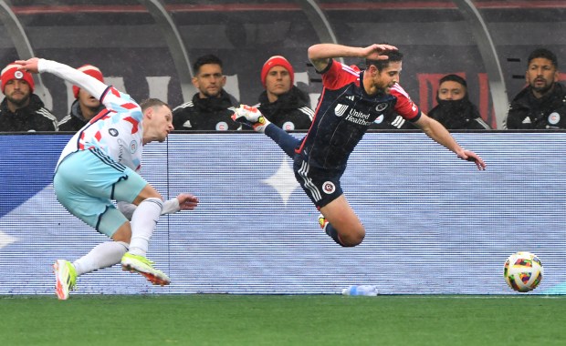 The Revolution's Matthew Polster, right, and Chicago Fire's Fabian Herbers lose their footing while pursuing the ball. (Chris Christo/Boston Herald)