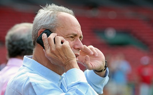 Red Sox President and CEO Larry Lucchino works the phone on the field at Fenway Park in 2012. (John Wilcox/Boston Herald/File)