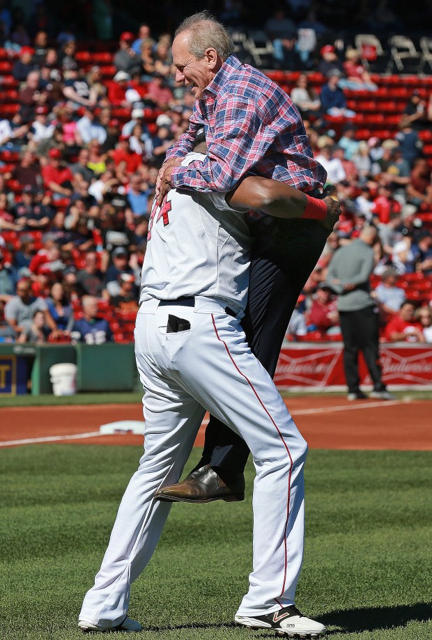 CARRY ON: Outgoing Red Sox president and CEO Larry Lucchino is picked up by David Ortiz after throwing out the ceremonial first pitch before the team's 2-0 win against the Orioles yesterday at Fenway Park. After the game (inset), Sox fans get autographed jerseys from players on the field.