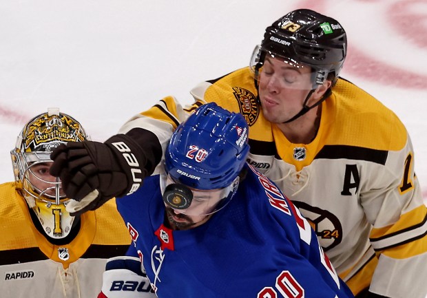 Boston Bruins defenseman Charlie McAvoy (73) attempts to knock the puck away from the face of New York Rangers left wing Chris Kreider during Thursday's battle in Boston. (Staff Photo/Stuart Cahill/Boston Herald)