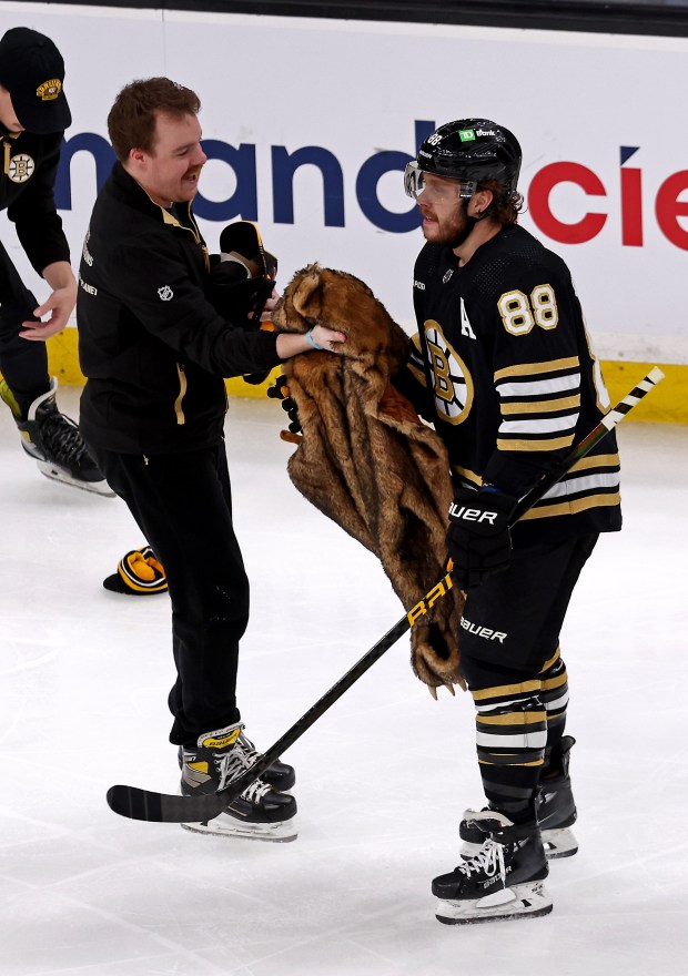 Bruins right wing David Pastrnak holds a bear skin coat which a fan threw onto the ice to celebrate his hat trick in Boston. (Staff Photo/Stuart Cahill/Boston Herald)