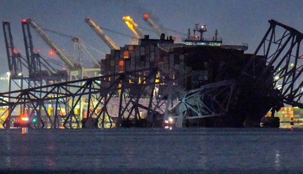 Emergency crews in boats examine the Francis Scott Key Bridge lies in ruins in the waters of the Patapsco River after a container ship collided with the structure overnight. (Karl Merton Ferron/Staff)