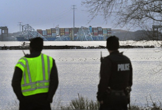 Baltimore County police officers on Bethlehem Boulevard look at the collapsed Francis Scott Key Bridge after it was struck by a container ship on Tuesday.(Kenneth K. Lam/Staff)