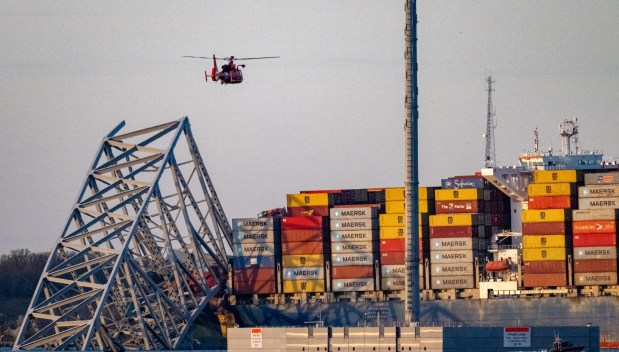 A Coast Guard helicopter flies over the Maersk container ship Dali and the remains of the collapsed Francis Scott Key Bridge. The massive container ship was adrift early Tuesday as it headed toward the iconic Francis Scott Key Bridge, losing power before colliding with one of the bridge's support columns. (Jerry Jackson/Staff)