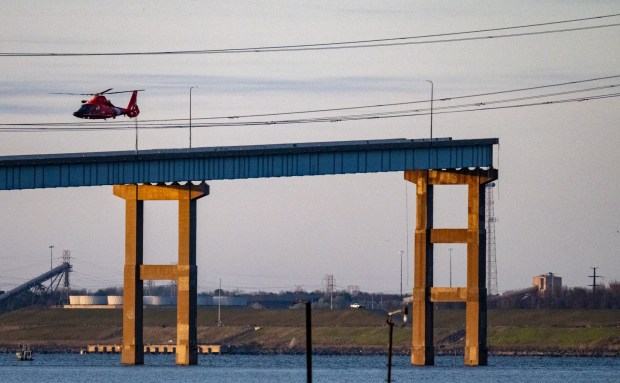 A Coast Guard helicopter flies over the remains of the collapsed Francis Scott Key Bridge. The massive container ship Dali was adrift early Tuesday as it headed toward the iconic Francis Scott Key Bridge, losing power before colliding with one of the bridge's support columns. (Jerry Jackson/Staff)